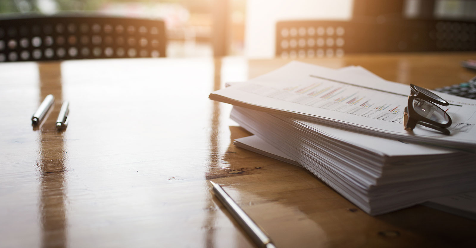 Glasses laying on top of paperwork on a desk