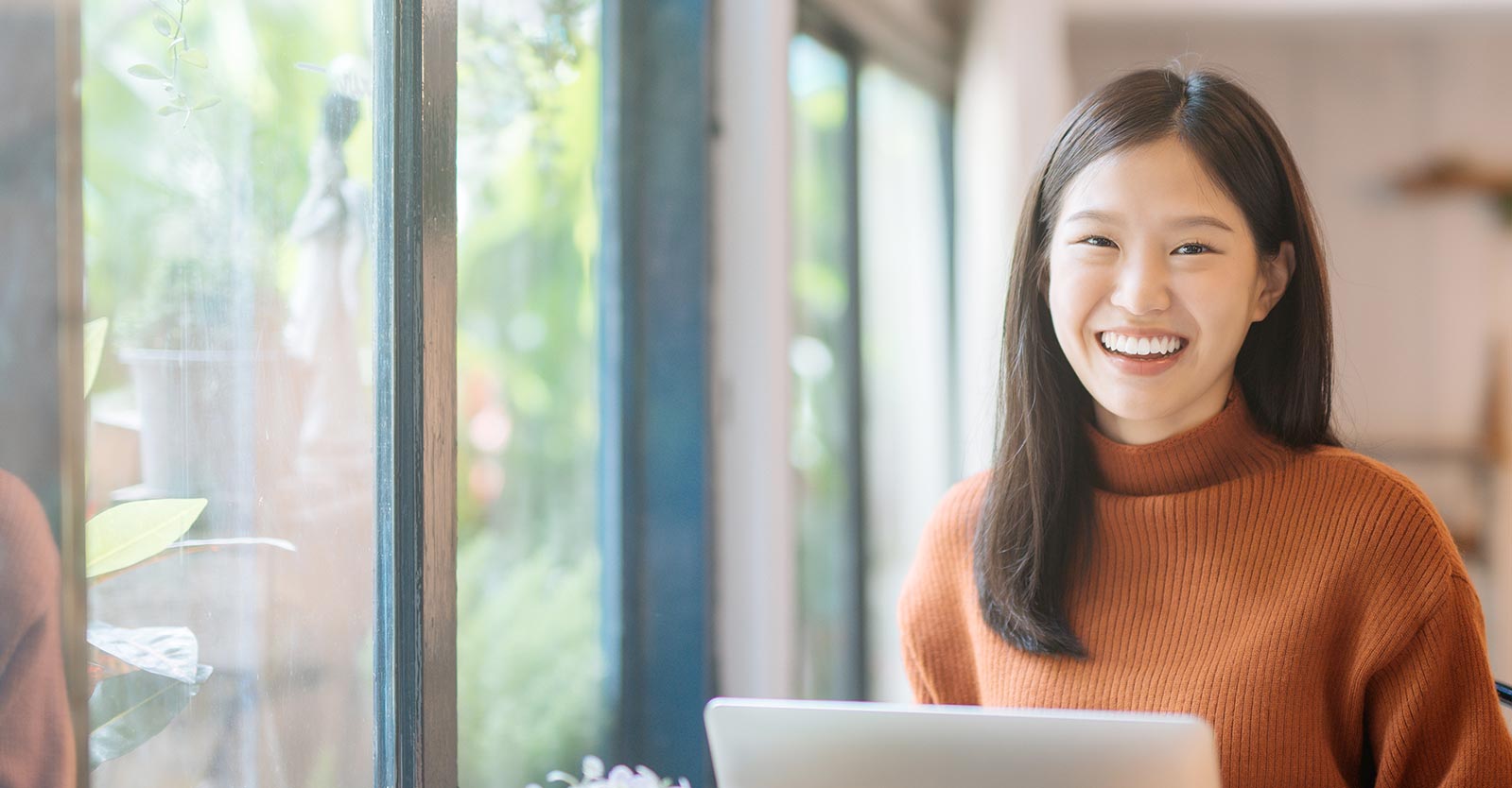 Woman sitting beside windows with laptop computer